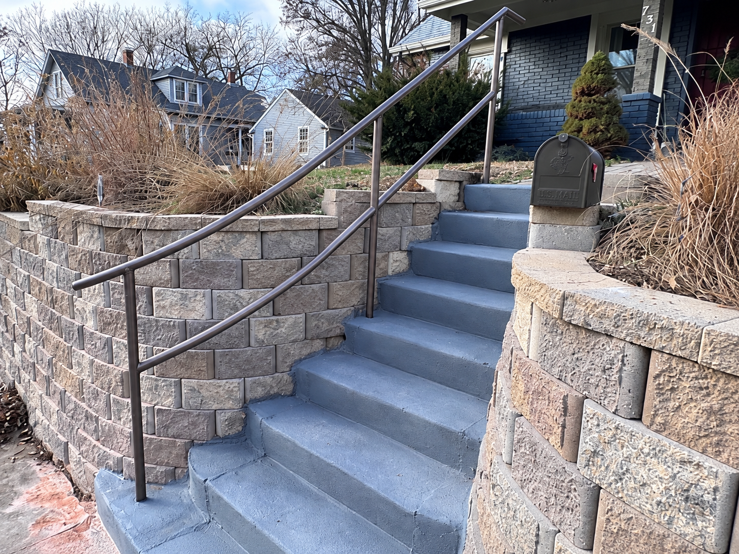 Pipe handrail following curved concrete front steps between retaining walls