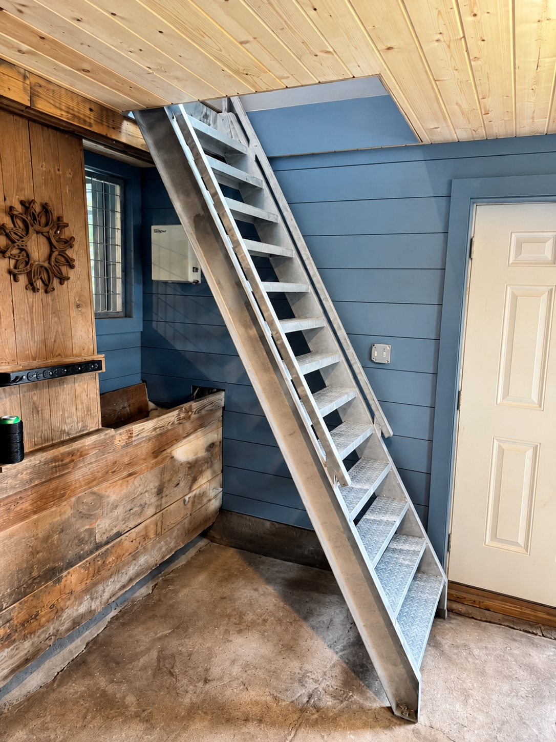 Galvanized steel stair assembly fitted inside a wood and blue-sided interior
