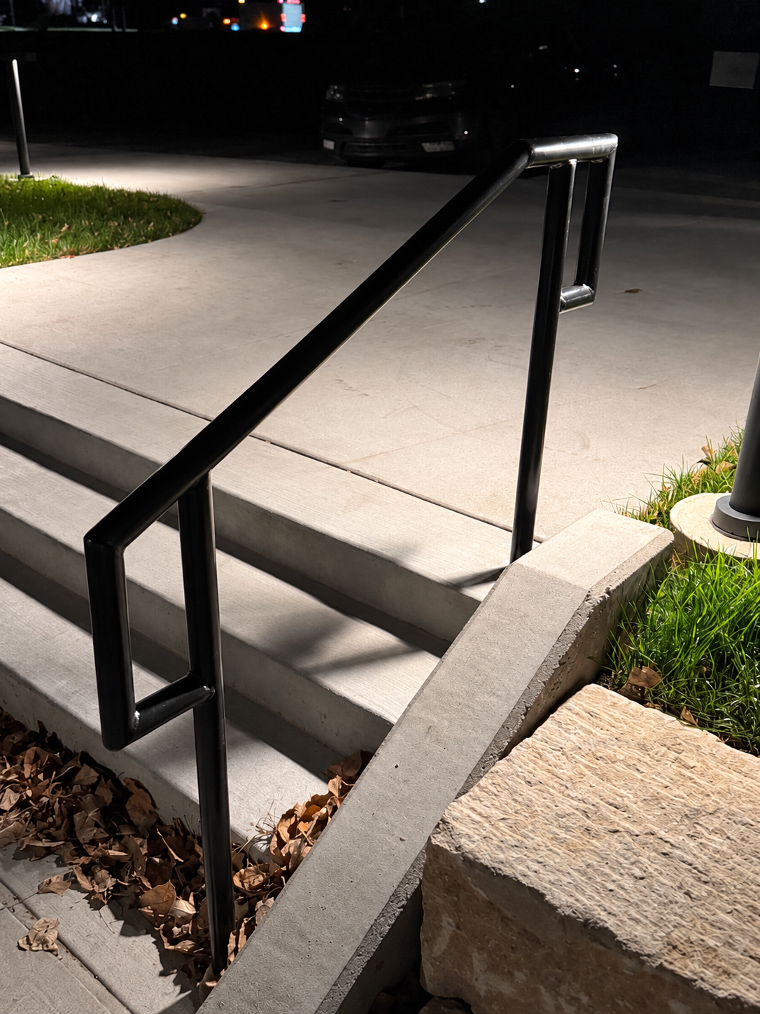 Black handrail installed along concrete steps at night